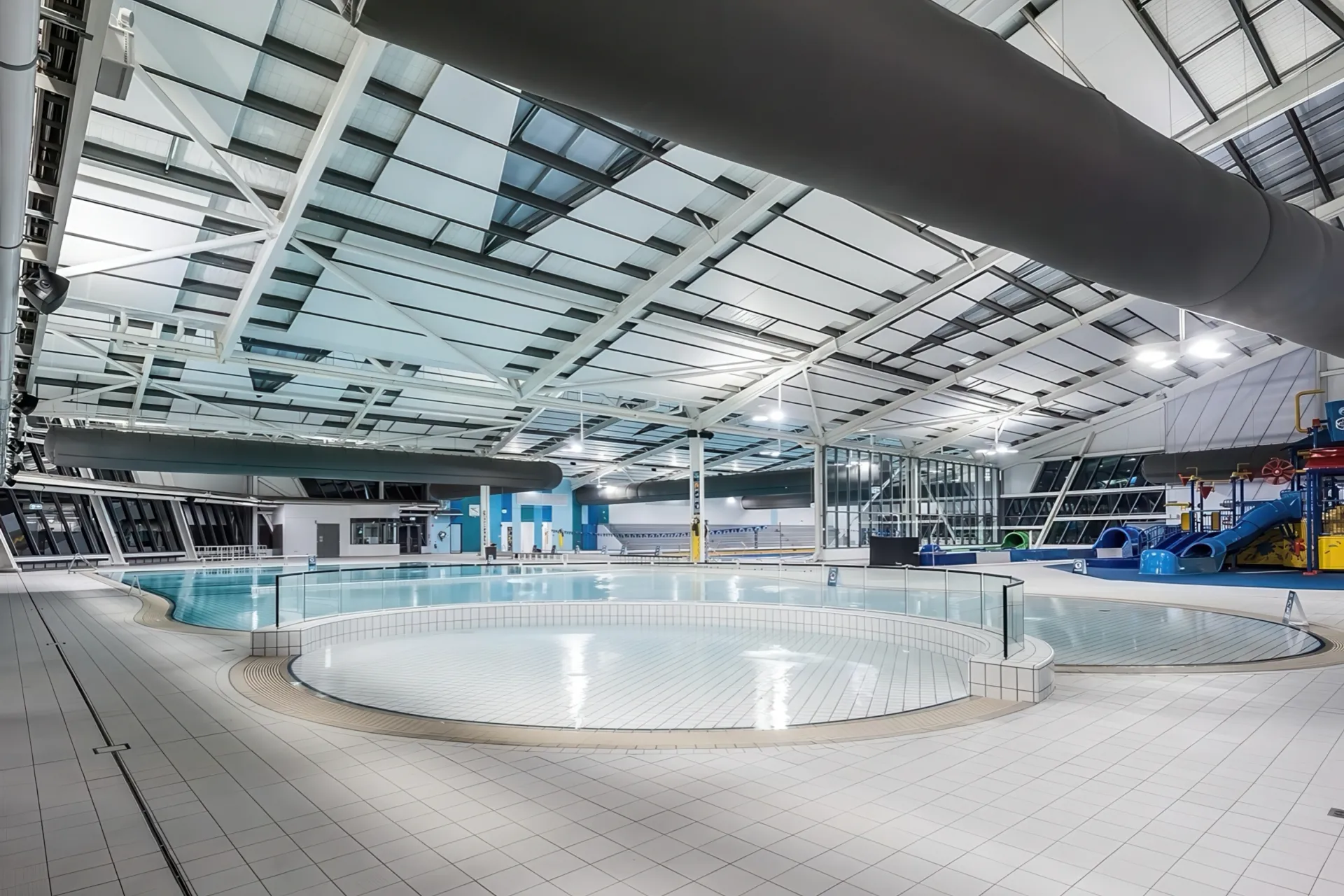 Aquatic centre interior — leisure pools beneath an expansive steel and skylight roof