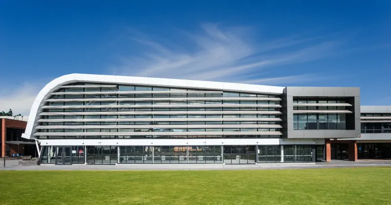Sports grandstand with a sweeping white curved roof above a green playing field