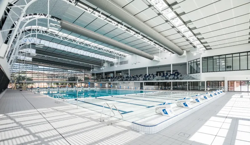 Indoor fifty metre competition swimming pool beneath an expansive white steel roof