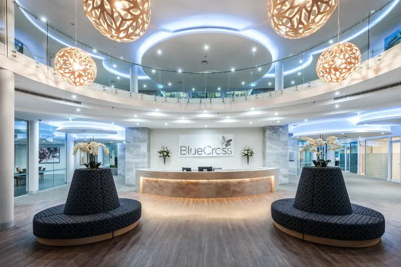 Double-height reception atrium with woven pendant lights and a curved timber desk
