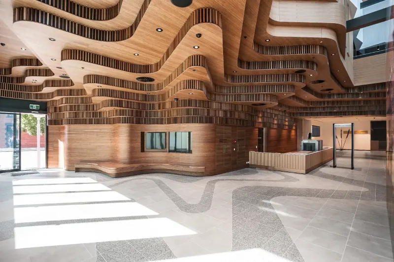 Public building foyer with an undulating stacked-timber wall and polished terrazzo floor