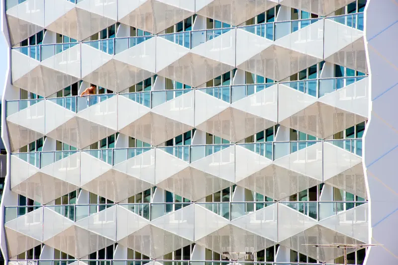 Repeating diamond balcony screens across an apartment facade