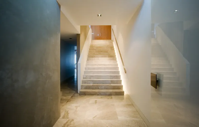 Minimal travertine stair and corridor with concealed cove lighting