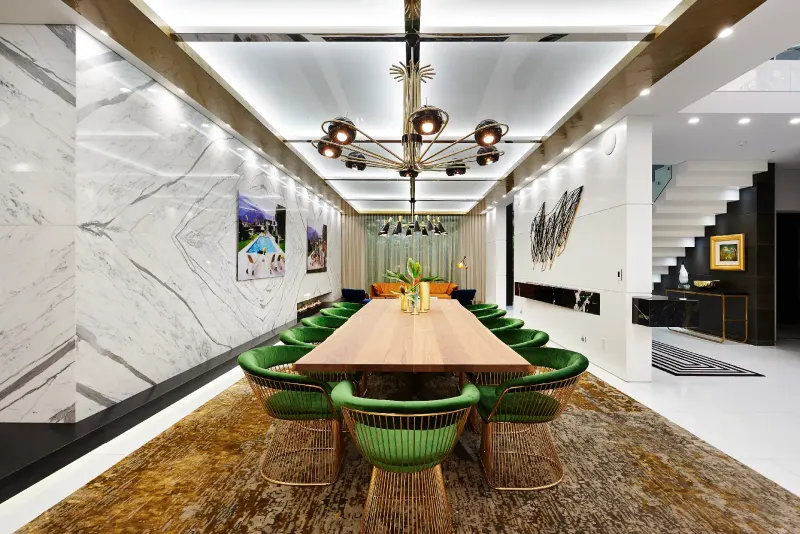 Formal dining room with marble walls, green velvet chairs and a sculptural chandelier